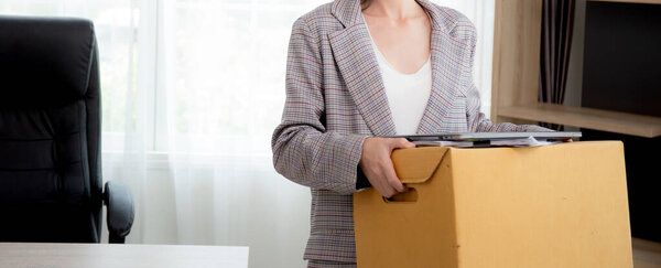 Portrait young woman employee carrying cardboard box or belonging with frustrated and stress while fired from job with despair, businesswoman resign with hopeless and sad, business and unemployment.