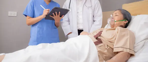 Specialist doctor and nurse explaining and check with elderly patient in hospital, medical and sick, diagnostic with report medical and health care on tablet, examining disease, senior and unwell.