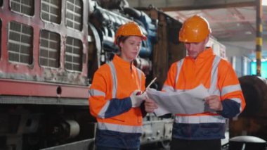 Kafkasyalı genç mühendis ve kadın tren şemasını kontrol ediyor. İstasyonun planlarını kontrol ediyor. Mühendis sistem ulaşımını denetliyor..