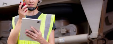 Kafkasyalı genç bir mühendis, radyo komutası altında çalışan bir işçiyle birlikte istasyonda elektronik trenin bakımını kontrol ediyor ve dijital tablete bakıyor, ulaşım ve altyapıyı kontrol ediyor..