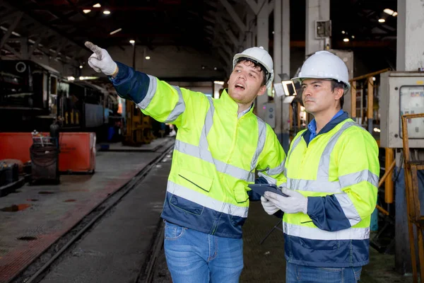 Team caucasian engineer checking train looking tablet in station, team engineer inspect system transport, technician examining infrastructure and talking with partner, transportation and industry.