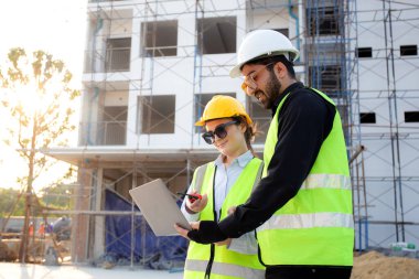 İnşaat sahasında teftiş ve planlama için dizüstü bilgisayar arayan mimar ya da mühendis ekibi, proje geliştirme evini inceleyen ve kontrol eden müteahhit ya da müteahhit, sanayi konsepti.