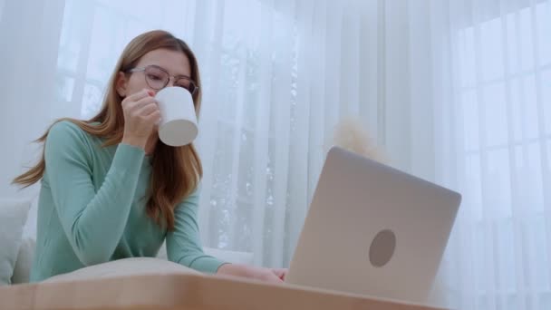 Młoda Azjatka Okularach Siedząca Sofa Pracująca Laptopie Pijąca Kawę Salonie — Wideo stockowe