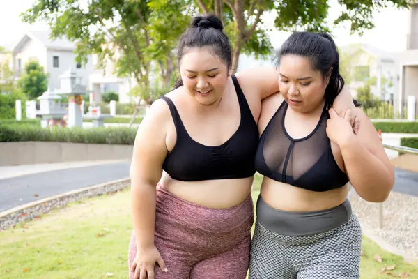 stock image Plus size asian woman accident with leg and sprain ankle while friends help and first aid at park, accident and hurt with foot during workout of fat woman, activity and emergency.