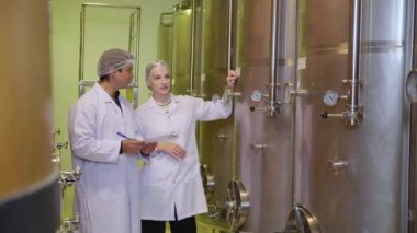 Şarap üreticisi ekip şaraphanedeki şarap üretimini kontrol ediyor ve inceliyor, müfettiş kaliteyi kontrol ediyor ve şarap deposunu depoda veya fıçıda mayalıyor, endüstriyel ve imalat konseptini inceliyor..