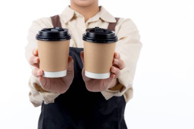 Barista 'lı genç Asyalı bir kadının önlüklü hali hazır kahve fincanını sunuyor, elleri izole edilmiş beyaz arka plana odaklanıyor, kahve barmeninin elinde tek kullanımlık kahve fincanı, küçük işletme ya da yeni başlayanlar..