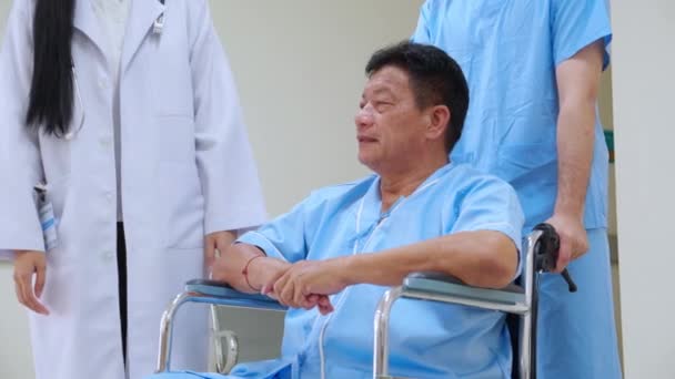 老年人坐在轮椅上 由医务人员在诊所或医院与医生交谈和讨论的亚洲老年男子病人 接受医生治疗的老年病人 — 图库视频影像
