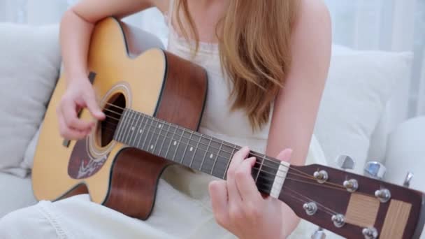 亚洲年轻女子在客厅里坐在沙发上弹奏吉他的小手 技巧与练习 吉他手与爱好 享受与放松 娱乐与生活方式 — 图库视频影像