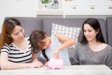 Anneye para biriktirmeyi öğretmek evde oturma odasındaki kanepede oturan domuzcuk bankasına para koyar, anne ve çocuk gelecek, ev ve para için para, aile kavramı için sermaye hakkında öğrenirler..