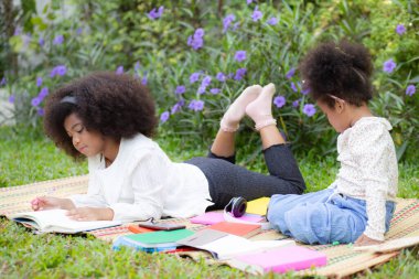 Bahçede bir hasırda uzanmış kitap okuyan iki çocuk, arka bahçede ödev yapan kardeşler, çocukların eğitimi ve öğrenimi, aile bağları, aile kavramının etkinliği.