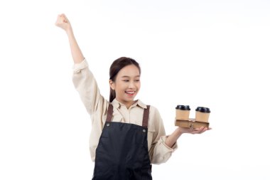Asyalı genç bir kadın kahve barmeni elinde bir kahve fincanı tutuyor. Heyecanlı, izole, beyaz bir arka planı var. Neşeli, mutlu bir barista..