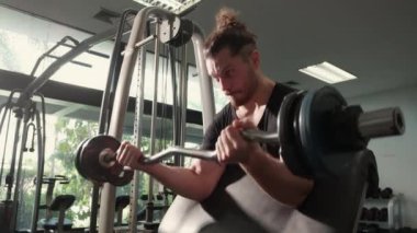 Genç beyaz adam spor salonunda motivasyon ve kararlılıkla çalışıyor. Ağırlıkları güçlü ve güçlü kaldırıyor. Halteri dayanıklılık ve spor konseptiyle kaldırıyor..