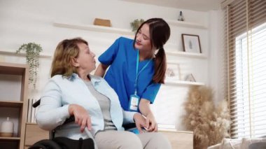 Bakıcı genç kadın tekerlekli sandalyede oturan yaşlılara bakıyor ve evdeki oturma odasında cesaretlendiriyor, doktorla son sınıf terapisi, hasta ve destekle doktor desteği, sigorta ve tıbbi destek..