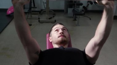 Genç beyaz adam spor salonunda motivasyon ve kararlılıkla çalışıyor. Ağırlıkları güçlü ve güçlü kaldırıyor. Halteri dayanıklılık ve spor konseptiyle kaldırıyor..