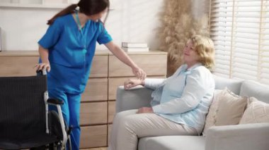 Bakıcı genç kadın tekerlekli sandalyede oturan yaşlılara bakıyor ve evde oturma odasında destek oluyor, hemşireyle son sınıf terapisi, hastayla ilgili doktor yardımı ve hizmet, sigorta ve tıbbi destek alıyor..