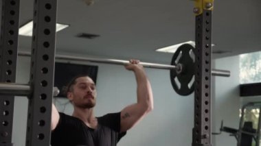 Genç beyaz adam spor salonunda motivasyon ve kararlılıkla çalışıyor. Ağırlıkları güçlü ve güçlü kaldırıyor. Halteri dayanıklılık ve spor konseptiyle kaldırıyor..