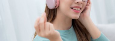 Kulaklık takmış, müzik dinleyen mutlu genç bir kadın. Oturma odasında eğleniyor ve eğleniyor. Eğlence dolu mutlu bir kadın, bir kişi, yaşam tarzı konsepti..