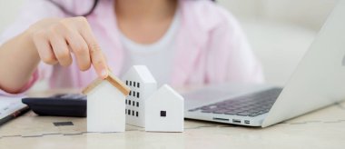 Young asian woman calculate cost and investment to finance about residential and real estate at home, female planning house tax and asset for assess and strategy to success, business and insurance.