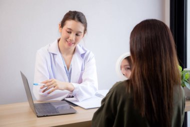 Genç Asyalı hasta kadın, modern tıp ofisinde dizüstü bilgisayar seyrederken, cilt ve kırışıklıkları hakkında doktorlara danışmanlık yapıyor, doktor yüz tanılama ve açıklama yapıyor..