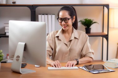 Mutluluk genç iş kadını masaüstü bilgisayarını evdeki oturma odasında kullanıyor, iş kadını internet, girişimci ya da serbest meslek ve iletişim için bilgisayar kullanıyor.