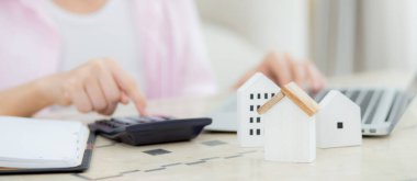Oturan, planlayan, hesap makinesi ve konut, konut sigortası ve konut, kredi ve ikamet bütçesi, iş ve mülk konsepti ile birlikte masraf ve ipotek hesaplayan kadınların yakın elleri.