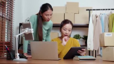 Tablet üzerinde çalışan iki genç Asyalı kadın çevrimiçi işleri yönetir ve planlarken ve evde siparişleri kontrol ederken, girişimci ve küçük işletme, çevrimiçi satıcı ile perakende satış, girişim işi.