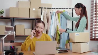 Genç Asyalı iş kadını laptopta çalışırken akıllı telefonlardan bahsederken ofis çalışanlarının siparişlerini kontrol ediyor, çevrimiçi satıcı, girişimci ve çevrimiçi dağıtım ile perakende satış yapıyor..