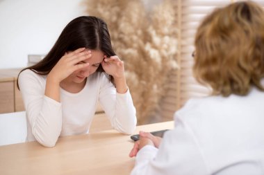 Genç Asyalı kadın terapisi modern tıp bürosunda kıdemli doktora danışmanlık, terapi, sağlık, sigorta ve sağlığı teşvik, stres ve depresyonlu hastalarla doktorluk danışmanlığı.