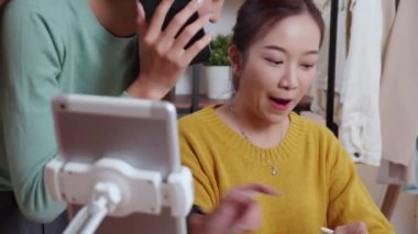 Tablet üzerinde çalışan iki genç Asyalı kadın çevrimiçi iş yaparken ve planlarken ve evde akıllı telefonla konuşarak siparişi kontrol ederken, çevrimiçi satıcı, girişimci ve kargo şirketiyle perakende satış yaparken,.
