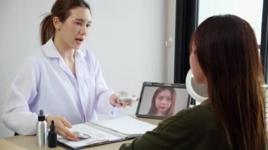 Genç Asyalı hasta kadın, doktor muayenesi için koluyla krem ya da losyon sürerken, cilt bakımı, tıp ve cilt bakımı ve cilt bakımı konusunda doktora danışmanlık yapıyor..