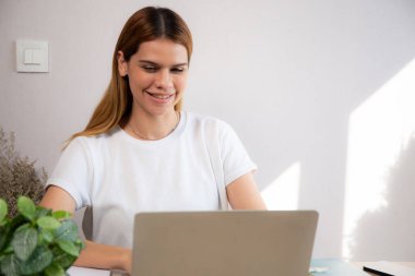 Genç iş kadınının ev ofisinin oturma odasında dizüstü bilgisayar kullanması, iş kadınının internet, girişimci ya da serbest çalışma, iş ve iletişim için dizüstü bilgisayar kullanması.