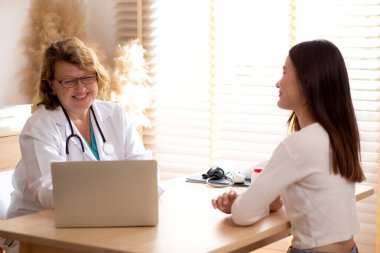 Modern tıp bürosundaki genç bir hastaya başhekim danışmanlık yapıyor. Doktor hastaya dizüstü bilgisayar, tıbbi ve sigortalardaki sağlık ve tedaviyi açıklıyor ve teşhis ediyor..