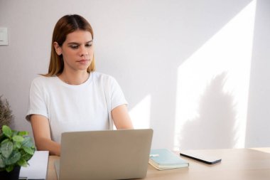 Genç iş kadınının ev ofisinin oturma odasında dizüstü bilgisayar kullanması, iş kadınının internet, girişimci ya da serbest çalışma, iş ve iletişim için dizüstü bilgisayar kullanması.