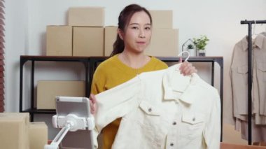 İki genç Asyalı kadın online giyim mağazasında yaşarken, evde sosyal tabletle giysi satışı yaparken, girişimci çevrimiçi kıyafet satışı ve sunumu için çevrimiçi satış yapıyor..