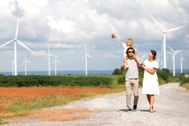 Mutluluk ailesi rüzgar türbini çiftliğinde yürürken, kızın babası birlikte, sürdürülebilirlik çevresi ve enerjisi, kaynak doğası ve sürdürülebilir çevresi, çevre ve aile bağları.