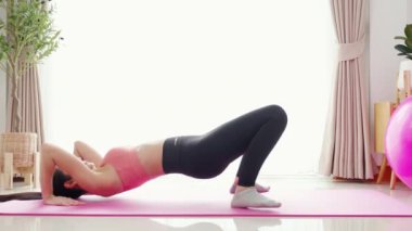 Evde yoga minderinde kaslarını esneterek yoga yapan Asyalı genç bir kadın, meydan okuma ve motivasyonla pilates yapan bir kadın, sağlık, spor ve refah için egzersiz yapan bir kadın..
