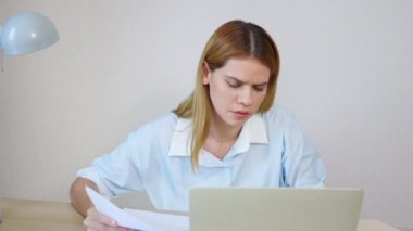 Kafkasyalı genç iş kadını, ev ofisinin oturma odasında masa başında dizüstü bilgisayar kullanırken, iş kadını ise defter, girişimci ya da serbest yazar, iş ve ticari amaçlı bilgisayar kullanıyor..