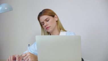 Kafkasyalı genç iş kadını, ev ofisinin oturma odasında masa başında dizüstü bilgisayar kullanırken, iş kadını ise defter, girişimci ya da serbest yazar, iş ve ticari amaçlı bilgisayar kullanıyor..