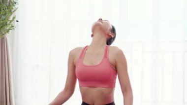 Güzel, genç Asyalı bir kadın evde ısınma egzersizi yapıyor ve boyun kaslarını esnetiyor. Spor, motivasyon ve sağlık ve spor konularında kararlı kadın egzersizleri yapıyor..