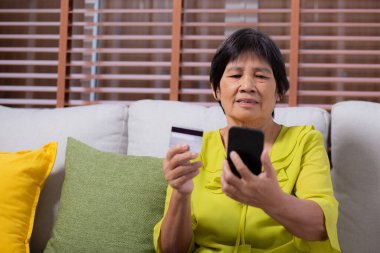 Kıdemli Asyalı kadın internet üzerinden akıllı telefon alışverişi yapıyor. İnternete kredi kartı alıyor. Akıllı telefon, alım-satım, ödeme, iş ve finans ile kadın ödemesi yapıyor..