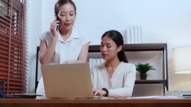 İki genç Asyalı iş kadını pazarlama ve finans hakkında planlama ve strateji yaparken, iş arkadaşları da akıllı telefon, toplantı ve dizüstü bilgisayarda ortaklık, iş ve danışmanlık konularında konuşuyorlar..