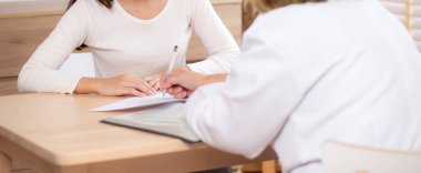 Genç kadın hasta danışmanlığı, modern tıp bürosunda belgeye bakarken hastalıklar, doktorluk, hastalarla sağlık, sağlık ve sigorta konularında konuşmak ve tartışmak.