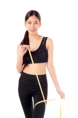 Spor giysili genç Asyalı kadın elinde bacağının ölçüsünü tutan izole edilmiş beyaz arka plan, kız kilo verme egzersizi ve egzersizle bacak, spor ve diyetle ölçüm yaparken egzersiz yapıyor..