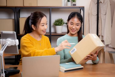 Çevrimiçi iş planlarken çalışan iki genç Asyalı kadın ve evde tablet ile sipariş kontrolü, çevrimiçi satıcı ile perakende satış, girişim işi ve kargo, nakliye ve hizmet.