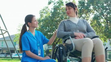 Kafkasyalı genç hemşire dışarıda tekerlekli sandalyede otururken hastayla rahatlıyor, doktor kadın desteği ve hasta ile danışmanlık yapıyor, yaşlı, tıbbi ve teselliye hizmet veriyor..