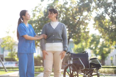 Kafkasyalı genç hemşire dışarıda parkta dururken hastayla rahatlıyor, doktor kadın hasta, hasta bakıcı ve hizmetleri ile destek ve danışmanlık yapıyor, yaşlı, tıbbi ve teselli edici.