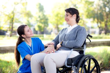 Kafkasyalı genç hemşire dışarıda tekerlekli sandalyede otururken hastayla rahatlıyor, doktor kadın desteği ve hasta, bakıcı ve hizmet, tıbbi ve teselli..