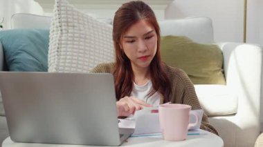 Genç Asyalı kadın, faturaları ve maliyetleri evdeki oturma odasında hesaplıyor. Masraflı ya da evrak işleriyle uğraşan kadın, beyan bankacılığı ve borç, kredi, iş ve mali durumları..