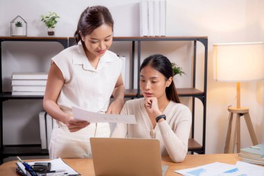 İki genç Asyalı iş kadını, iş ortağı, iş ortağı ve danışmanlık ile dizüstü bilgisayar ve belge arayan iş arkadaşları ile pazarlama ve finans hakkında planlama ve strateji yapıyor..