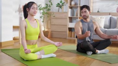 Genç Asyalı çift evdeki oturma odasında yoga ve meditasyon yapıyor. Rahatlama, sağIık ve sağlıklı yaşam için kadınla yoga hocası, yoga ve sağlık sporu yapıyor..